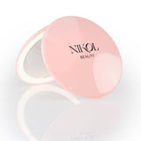 The Nikol Beauty 10x Magnification Mirror is a round, pink compact with the brand name on the lid, partially open to display its precise mirror, shown against a white background—perfect for detailed makeup touch-ups.