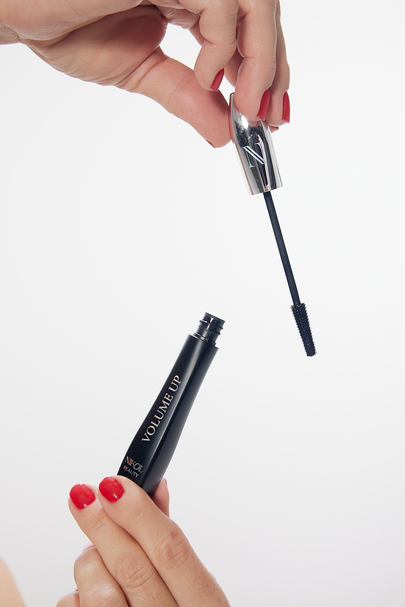 Hands holding the open VOLUME UP Mascara tube and its wand
