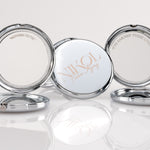 Three round, silver Fierce Aging Mini Compact Mirrors from Nikol Beauty stand open—one reads NIKOL Faster Aging, while the sides say NOTHING TO FIX and I’VE EARNED THESE LINES!, celebrating confidence and portable beauty.
