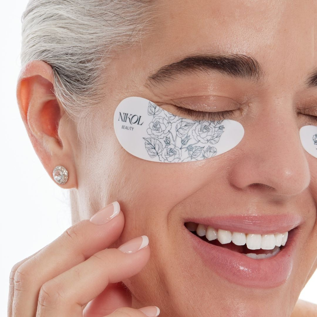 Close-up of Nikol laughing with eyes closed, wearing a reusable floral silicone eye mask under her eye