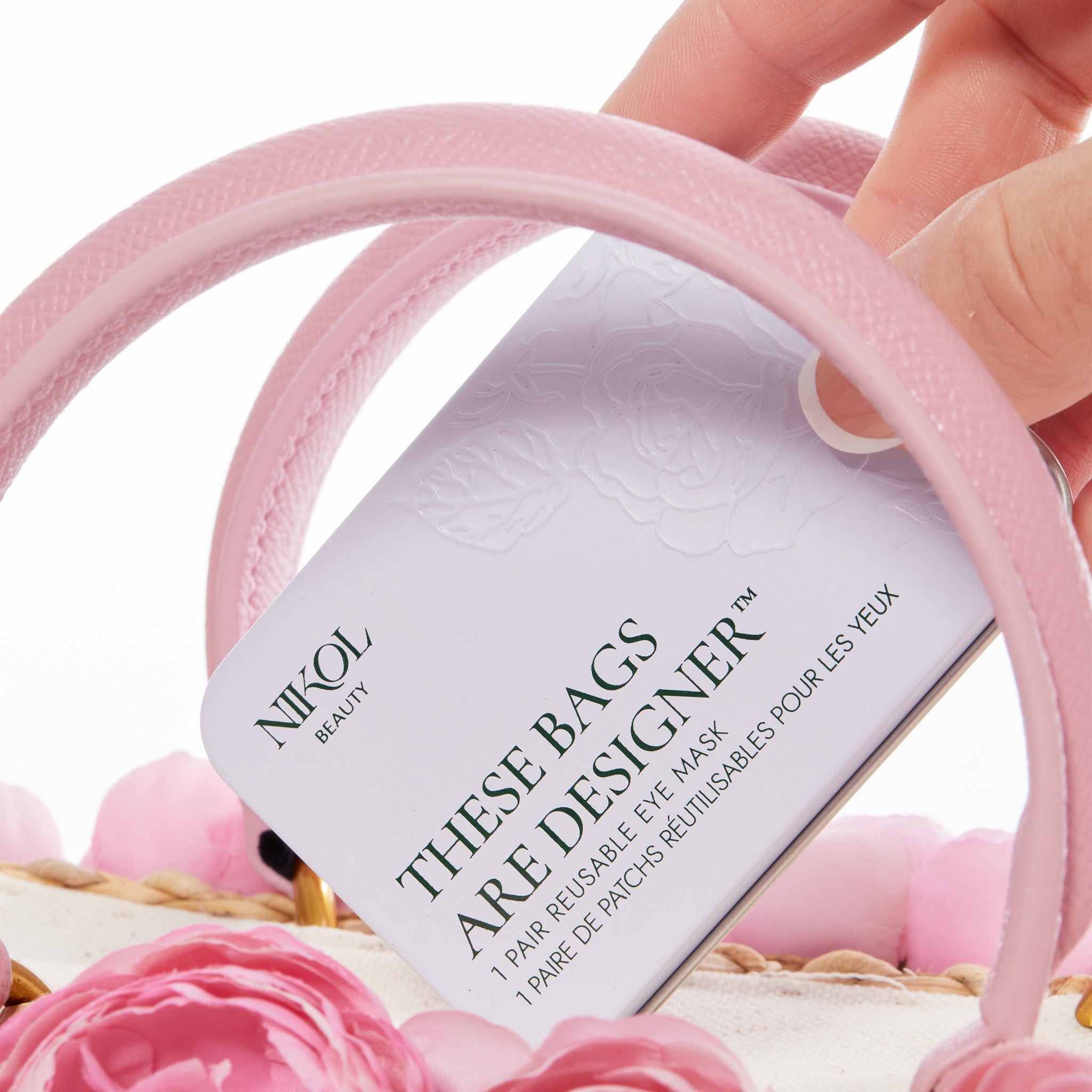 The These Bags Are Designer tin tucked into a pink handbag above a bed of pink roses