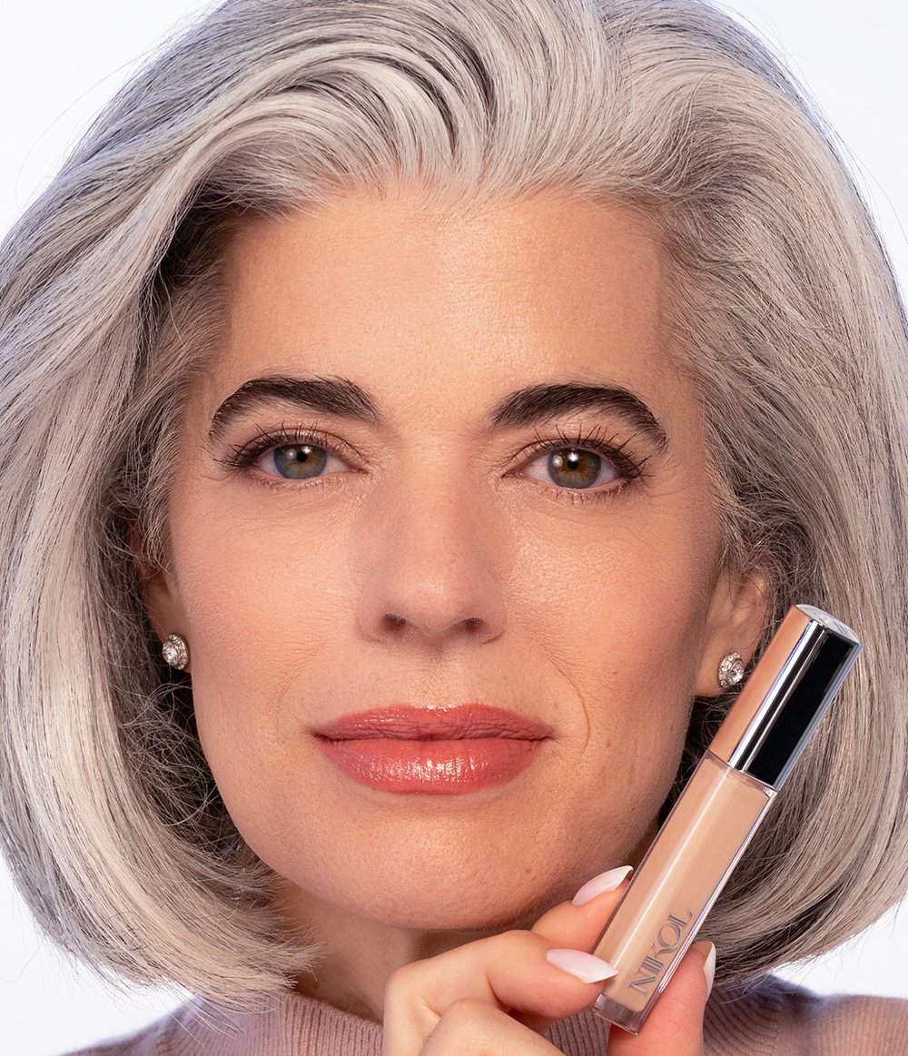 Model holding a tube of the Creamy Concealer beside her face