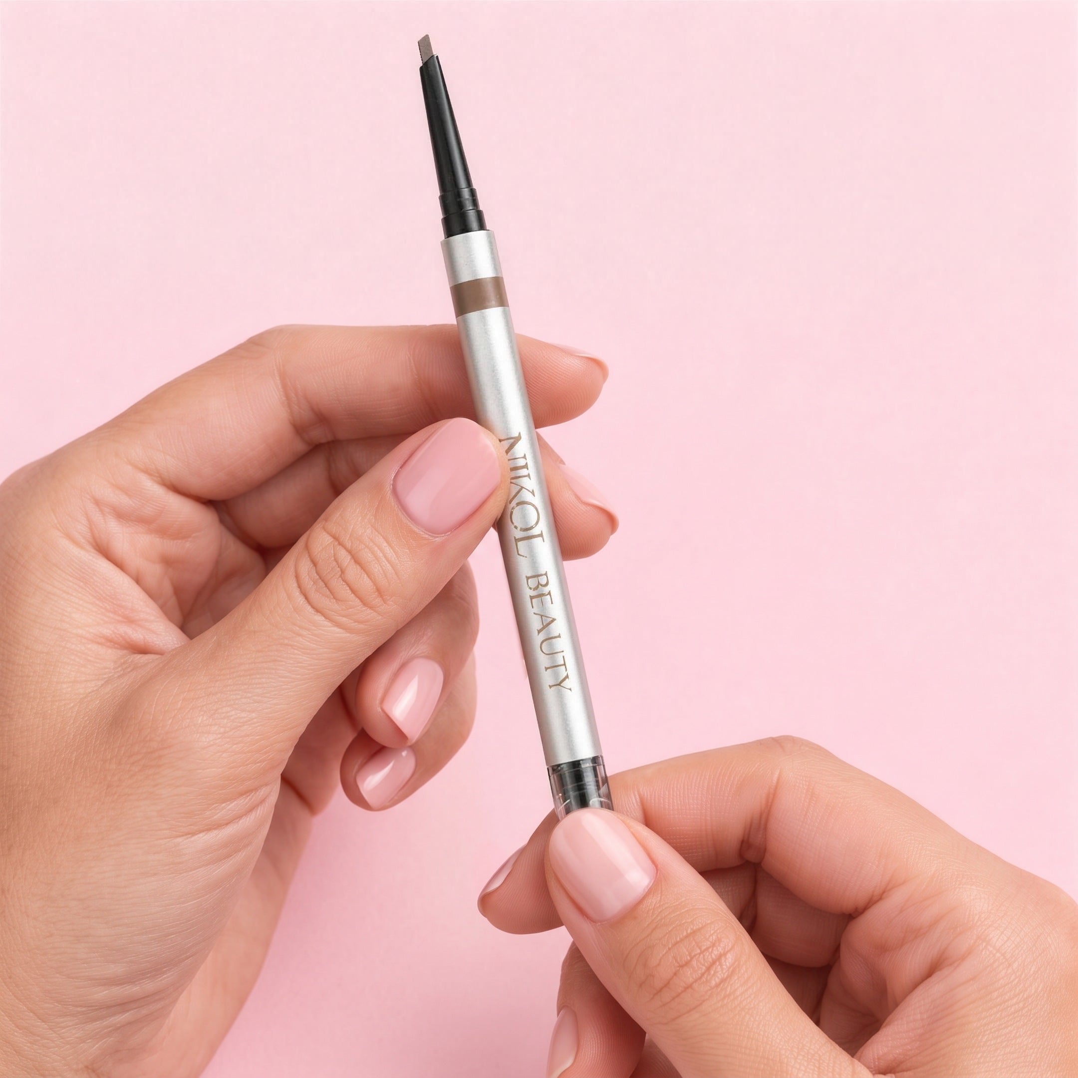 Manicured hands with pink nail polish twisting up the fine tip of the Skinny Brow Pencil, no sharpener needed
