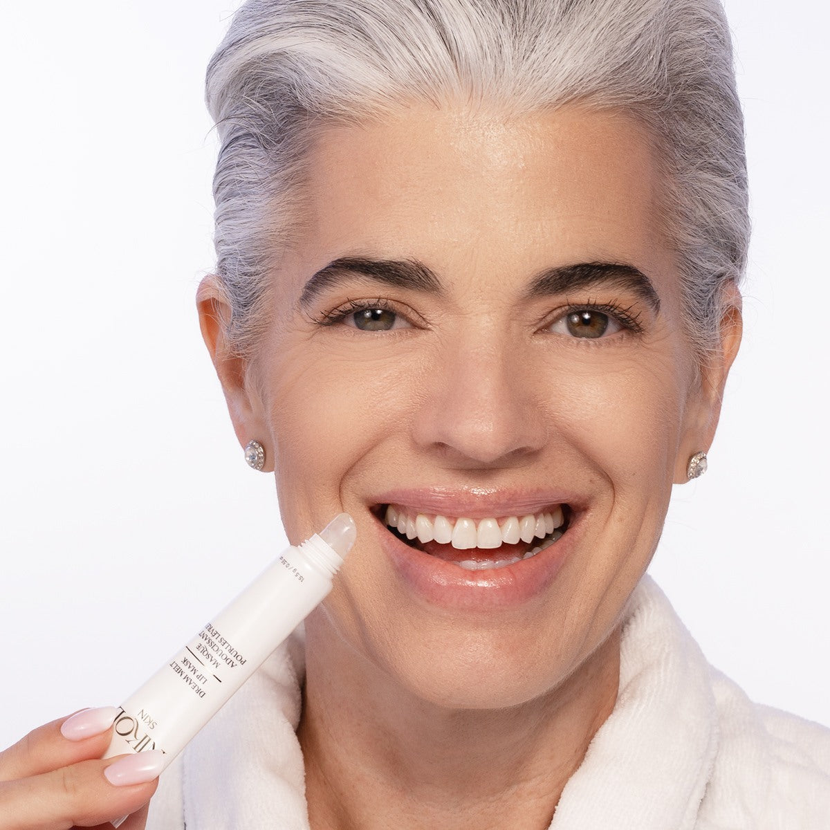 Nikol smiling while holding the Dream Melt Lip Mask tube up to her lips