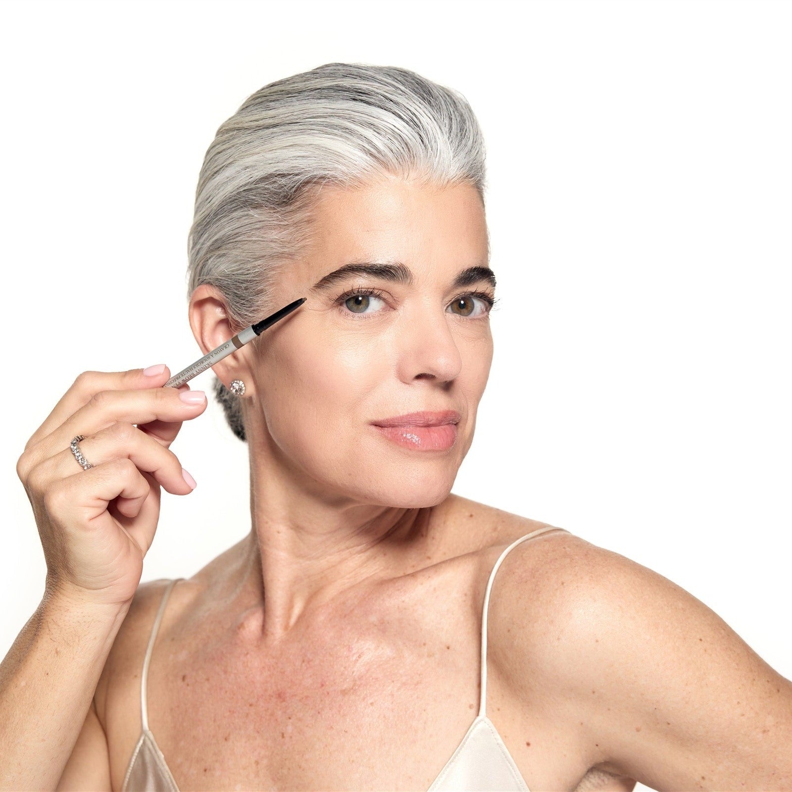 Nikol, with silver hair, brushing Brow Mascara through her brow