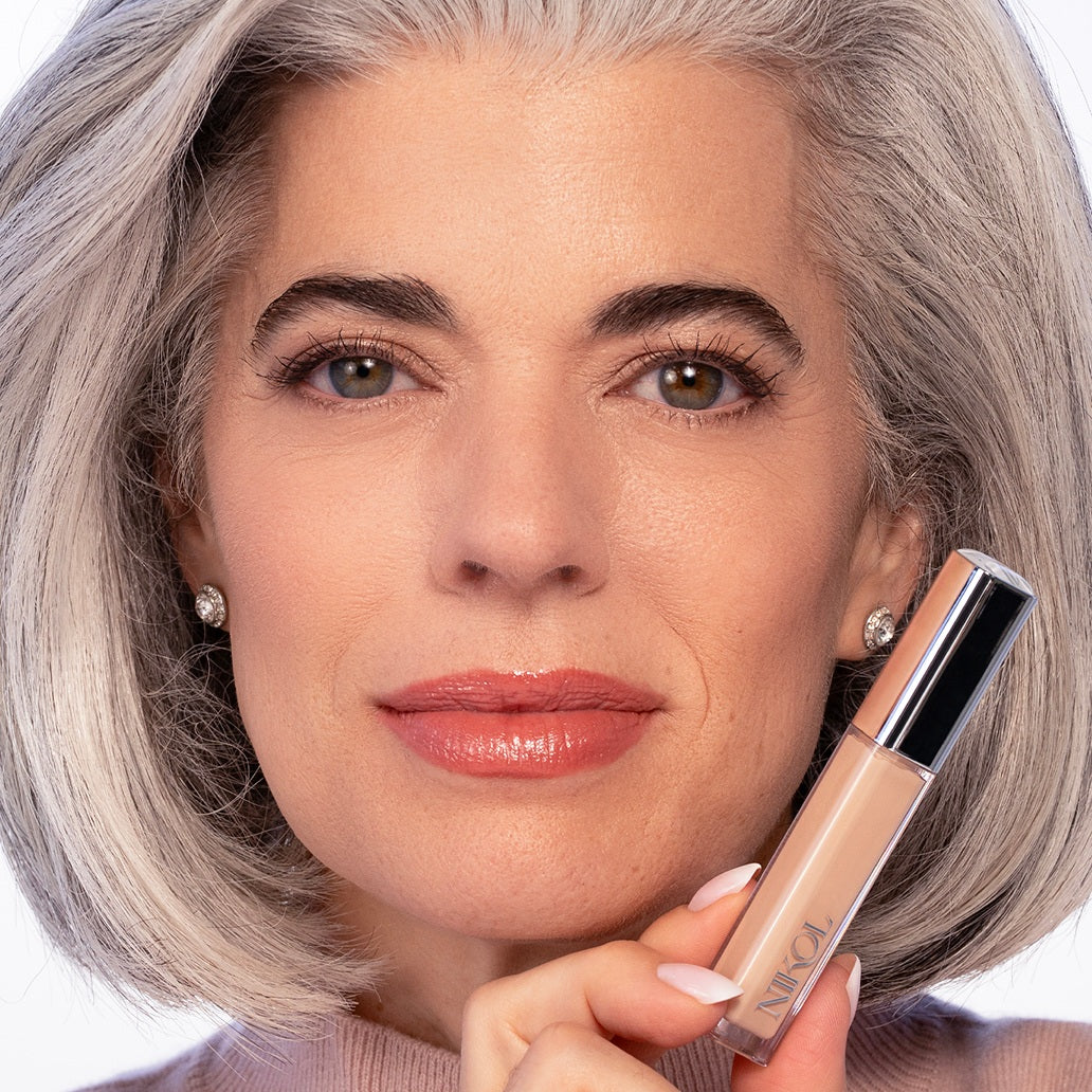 Model holding a tube of the Creamy Concealer beside her face